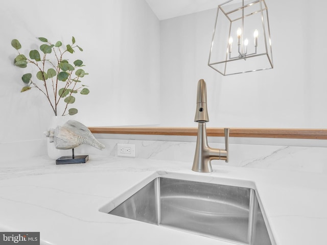 room details with light stone counters, hanging light fixtures, and sink