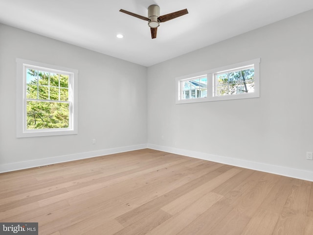 empty room with ceiling fan, a wealth of natural light, and light hardwood / wood-style flooring