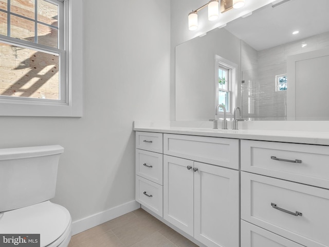 bathroom featuring vanity, toilet, and a tile shower