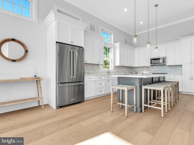 kitchen featuring decorative light fixtures, white cabinetry, backsplash, and appliances with stainless steel finishes