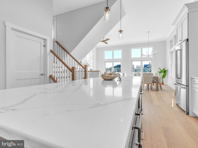 kitchen featuring light stone countertops, white cabinetry, hanging light fixtures, and high end refrigerator