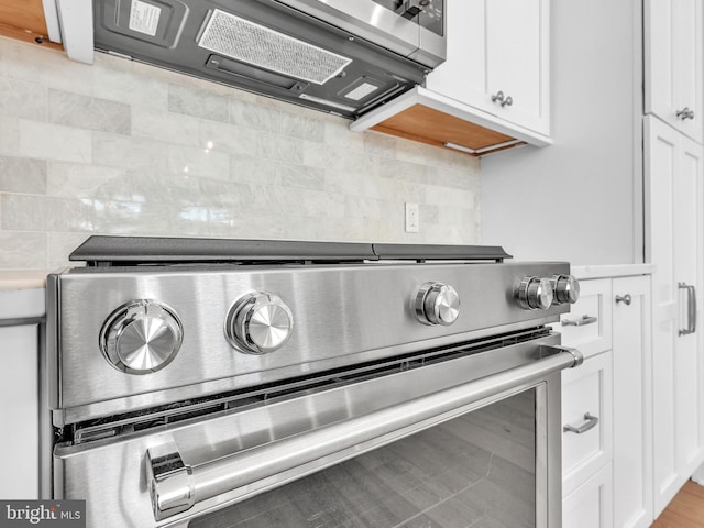 room details featuring stainless steel stove, white cabinetry, and tasteful backsplash