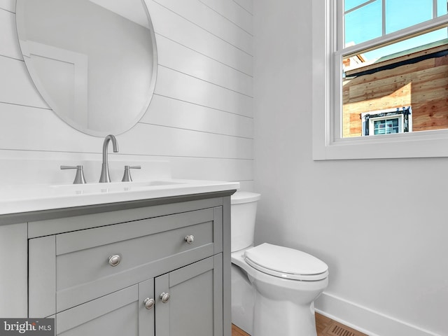 bathroom with vanity, toilet, and a healthy amount of sunlight