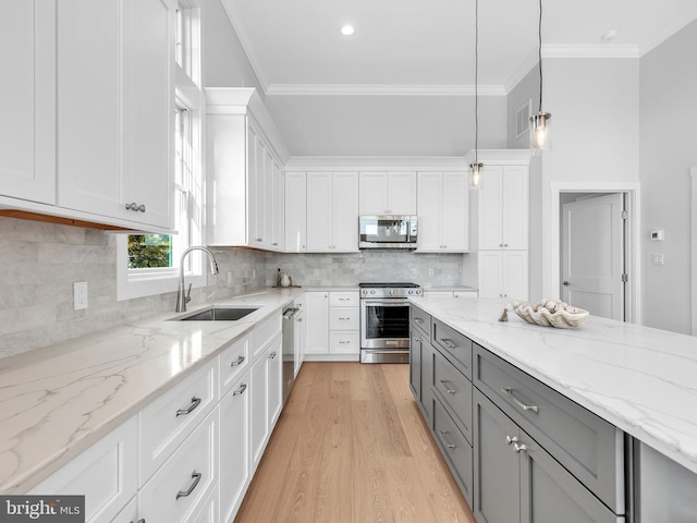 kitchen featuring light stone countertops, stainless steel appliances, sink, decorative light fixtures, and white cabinets