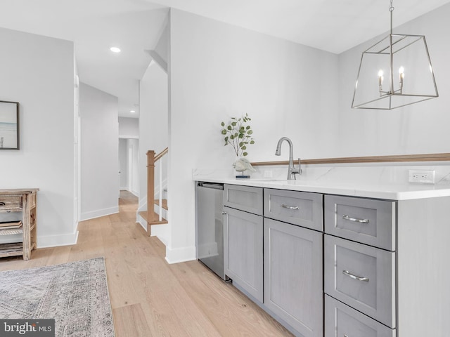 kitchen featuring light stone counters, gray cabinetry, light hardwood / wood-style flooring, dishwasher, and hanging light fixtures