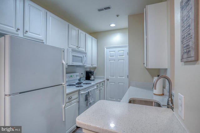 kitchen featuring sink, kitchen peninsula, white cabinetry, and white appliances