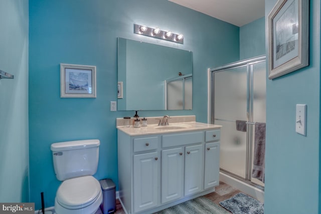 bathroom with a shower with door, toilet, and vanity