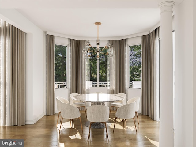 dining space featuring light hardwood / wood-style floors, ornate columns, and an inviting chandelier