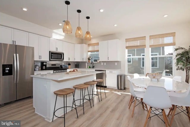 kitchen with white cabinetry, appliances with stainless steel finishes, hanging light fixtures, and a kitchen island