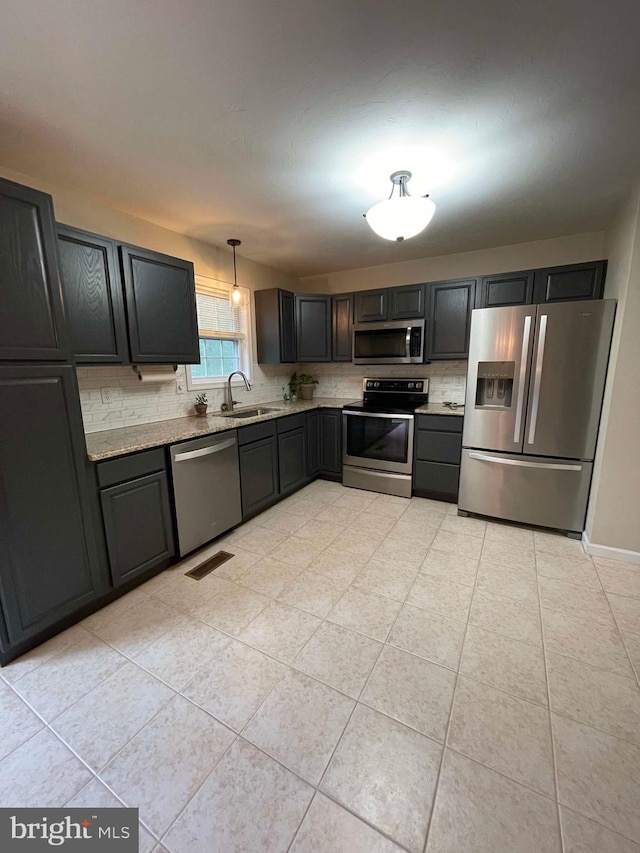 kitchen featuring appliances with stainless steel finishes, decorative light fixtures, backsplash, sink, and light tile patterned flooring