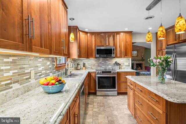 kitchen featuring light stone counters, decorative light fixtures, backsplash, stainless steel appliances, and sink