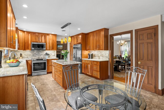 kitchen with appliances with stainless steel finishes, backsplash, light stone counters, and a kitchen island