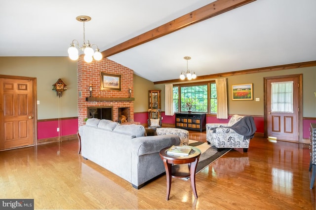 living room featuring hardwood / wood-style floors, a fireplace, a chandelier, and brick wall