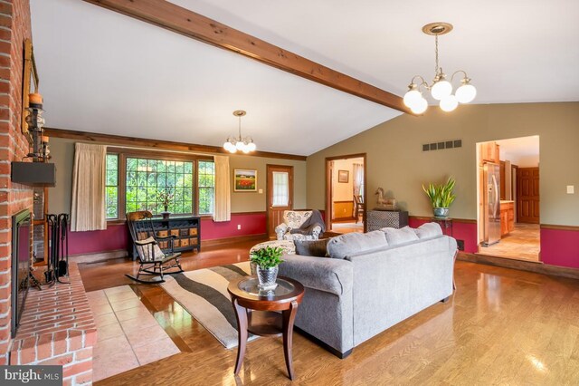 living room with wood-type flooring, a chandelier, vaulted ceiling with beams, and brick wall