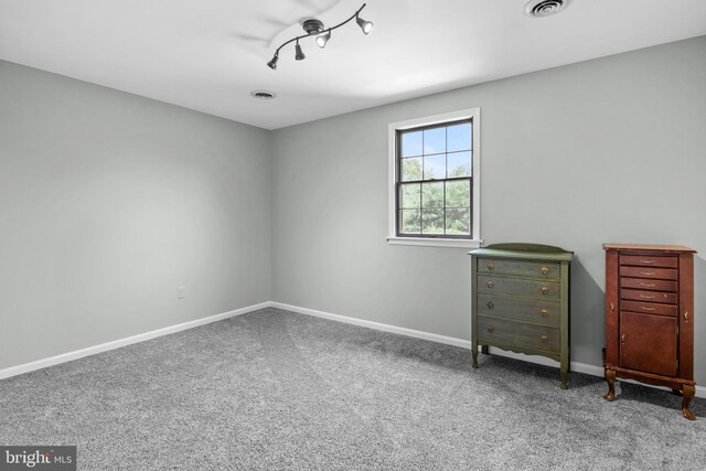 unfurnished bedroom with track lighting and carpet