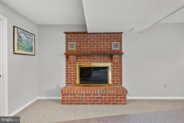 unfurnished living room featuring a brick fireplace, brick wall, and carpet