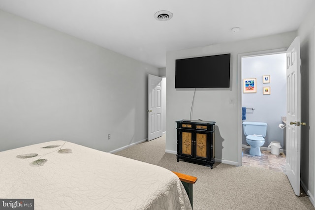 bedroom with ensuite bathroom and light carpet