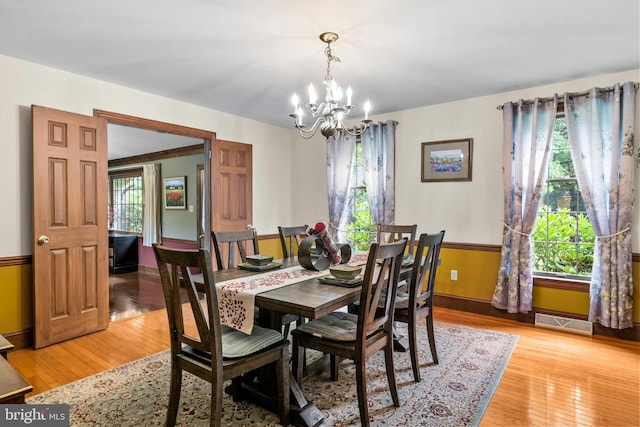 dining area with light hardwood / wood-style flooring and a notable chandelier