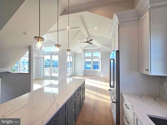 kitchen featuring pendant lighting, ceiling fan, vaulted ceiling with beams, light stone countertops, and white cabinetry