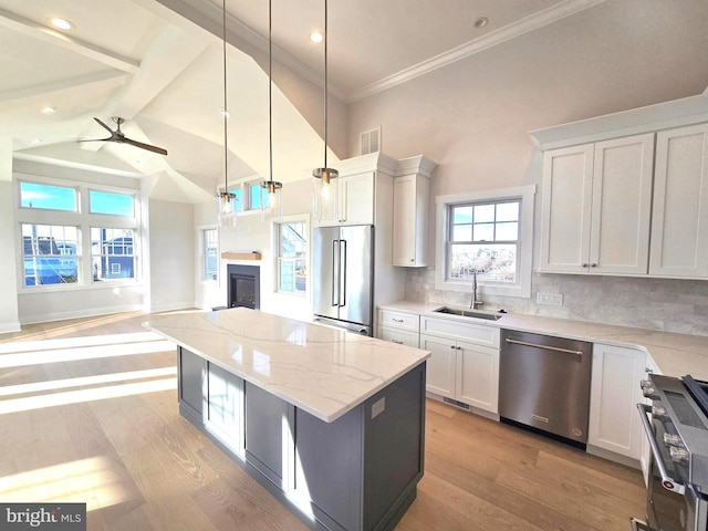 kitchen featuring backsplash, sink, hanging light fixtures, white cabinetry, and stainless steel appliances