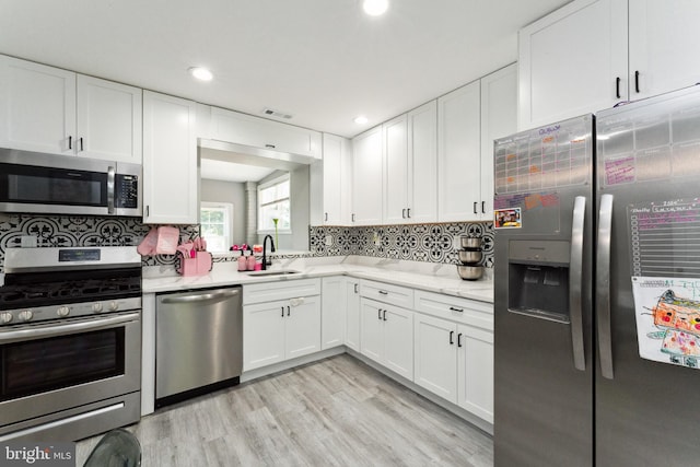 kitchen with sink, decorative backsplash, stainless steel appliances, and light hardwood / wood-style floors