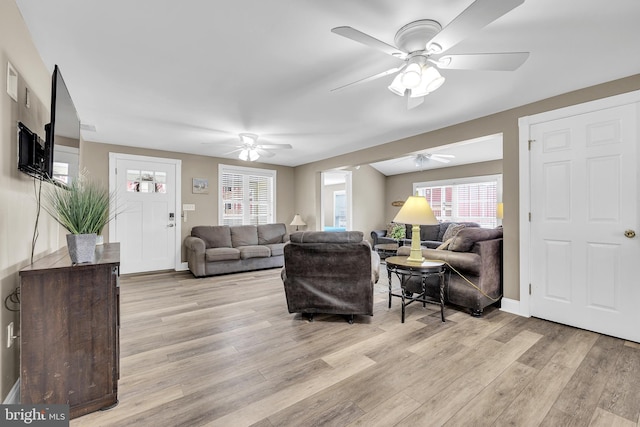 living area featuring ceiling fan, light wood-style flooring, and baseboards