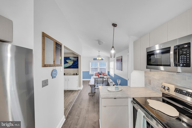 kitchen with ceiling fan, backsplash, dark hardwood / wood-style floors, appliances with stainless steel finishes, and decorative light fixtures