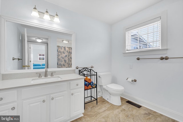 bathroom featuring toilet, vanity, visible vents, and baseboards