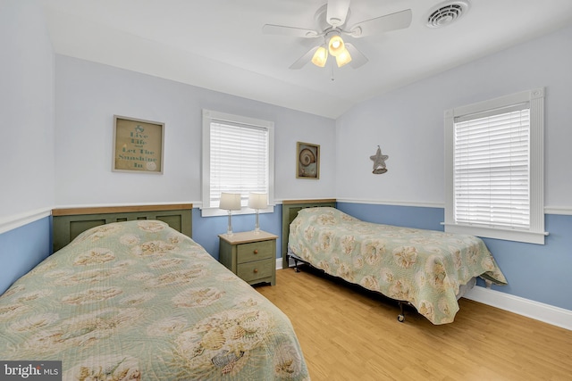 bedroom featuring ceiling fan, multiple windows, and light wood-type flooring