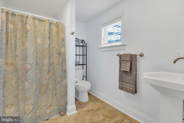 full bath featuring a sink, toilet, and baseboards