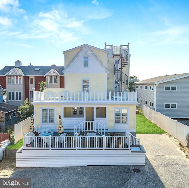 view of front of house featuring a balcony, stairs, a residential view, and fence