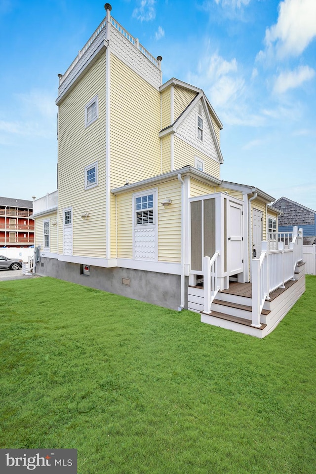 rear view of house featuring a deck and a lawn