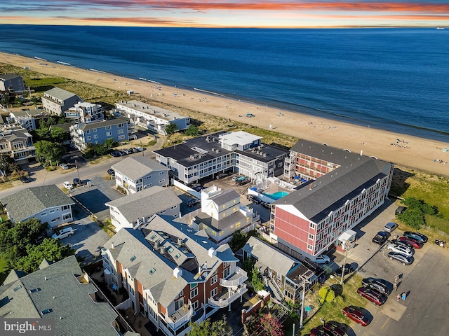 aerial view at dusk with a water view and a view of the beach