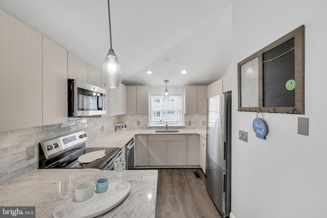 kitchen with tasteful backsplash, light stone counters, hanging light fixtures, stainless steel appliances, and a sink