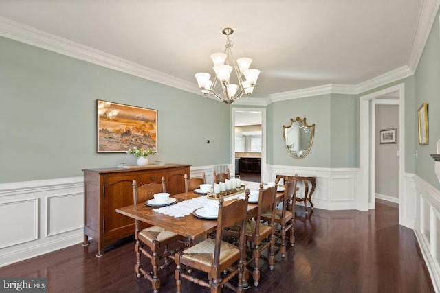 dining area featuring a wainscoted wall, dark wood-type flooring, an inviting chandelier, and ornamental molding