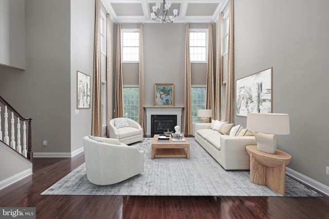 living area featuring a high ceiling, wood finished floors, baseboards, and coffered ceiling