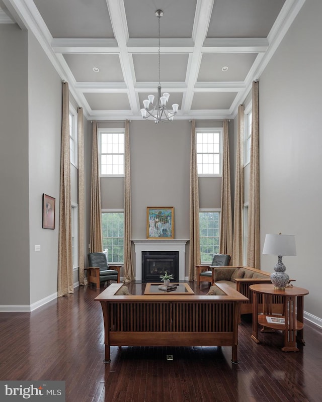 sitting room with a healthy amount of sunlight, a towering ceiling, and hardwood / wood-style floors