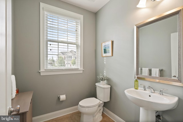 half bathroom with tile patterned floors, toilet, baseboards, and a sink