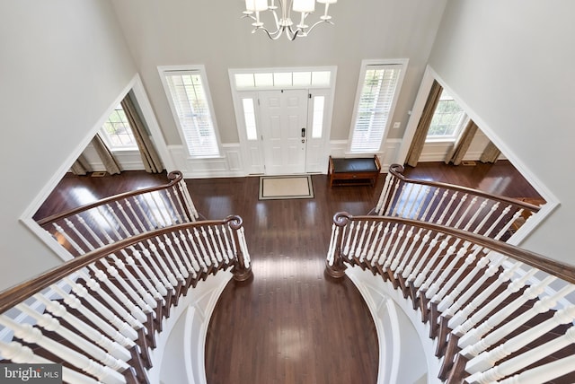 entrance foyer with wood finished floors, wainscoting, a chandelier, and a healthy amount of sunlight