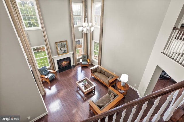 living room with a fireplace with flush hearth, wood finished floors, a high ceiling, a chandelier, and stairs