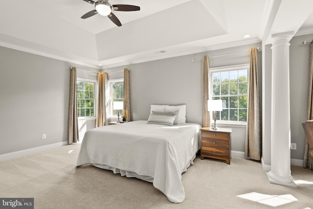 bedroom with light colored carpet, baseboards, a tray ceiling, and ornate columns