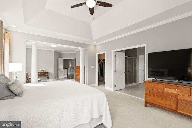 bedroom featuring a spacious closet, light carpet, a raised ceiling, and ornate columns