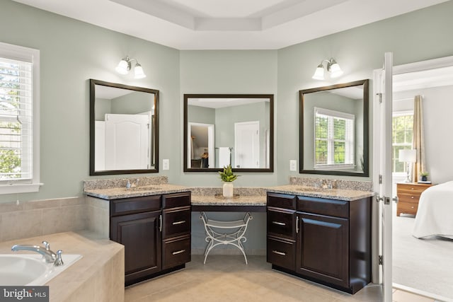 ensuite bathroom with a wealth of natural light, vanity, and tile patterned flooring