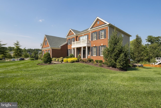 colonial home featuring a front lawn, a balcony, and brick siding