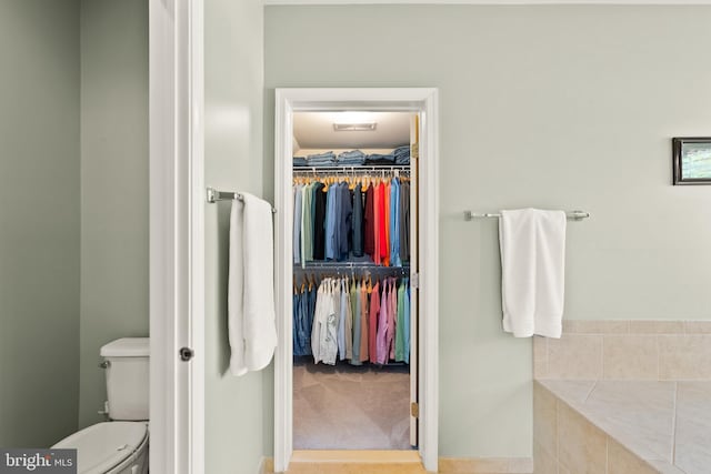 bathroom with a walk in closet and toilet