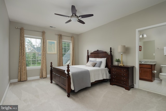 bedroom with visible vents, a ceiling fan, connected bathroom, baseboards, and light colored carpet