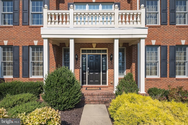 entrance to property featuring brick siding and a balcony