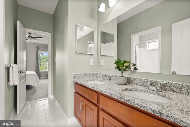 bathroom featuring tile patterned flooring, double vanity, baseboards, and a sink