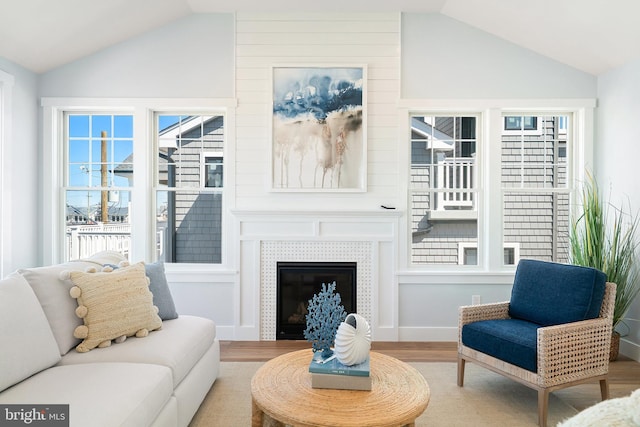 living room with a tile fireplace, vaulted ceiling, and wood finished floors