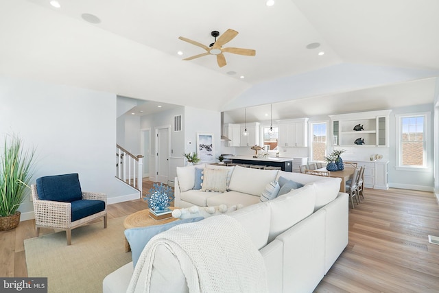 living room featuring lofted ceiling, stairway, a ceiling fan, light wood-style floors, and baseboards